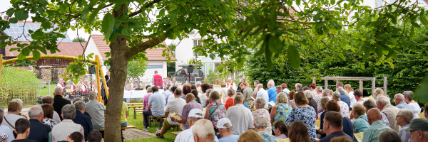 Gruppe von Menschen, die im Freiluftgottesdienst auf Bänken sitzt